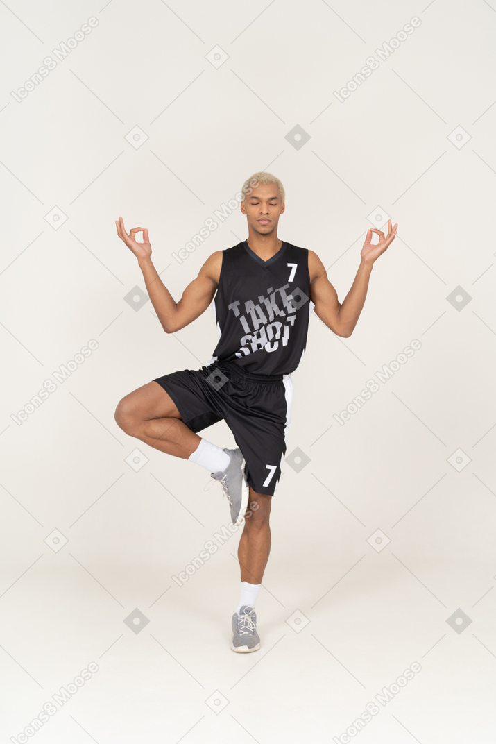 Vista frontal de um jovem jogador de basquete masculino meditando