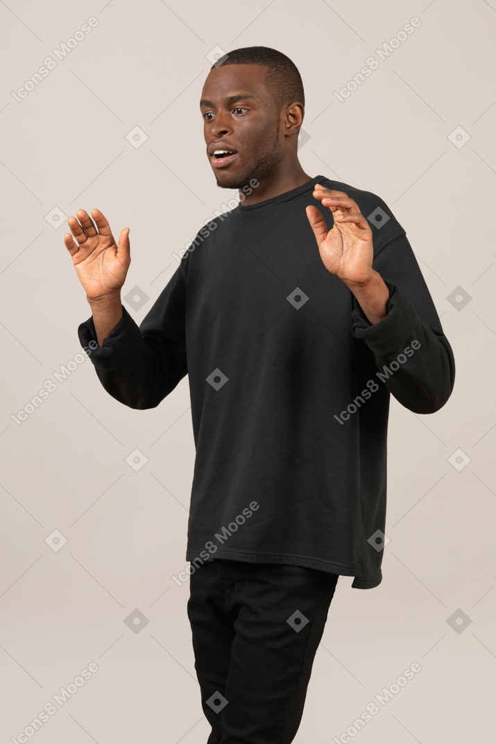 Surprised young man raising hands