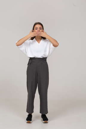 Vue de face d'une jeune femme en vêtements de bureau cachant sa bouche