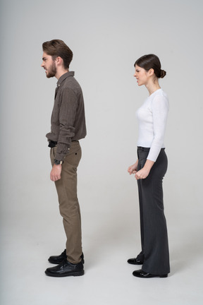 Vista lateral de una pareja furiosa en ropa de oficina apretando los puños