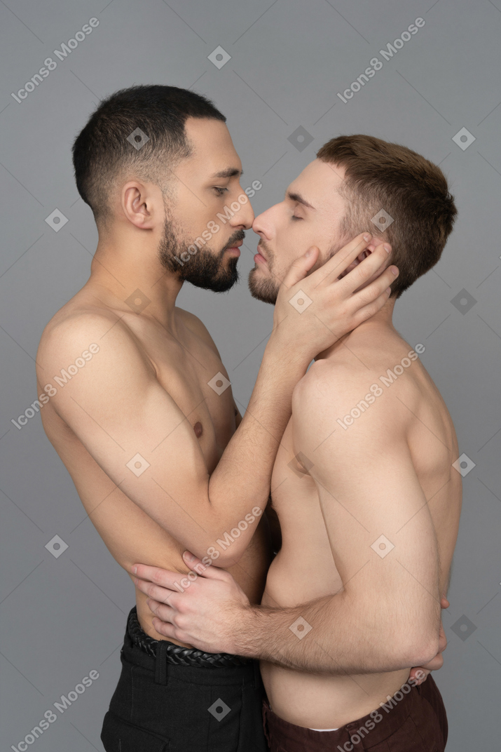 Primo piano di due uomini caucasici a torso nudo in piedi molto vicini e che si toccano delicatamente il naso