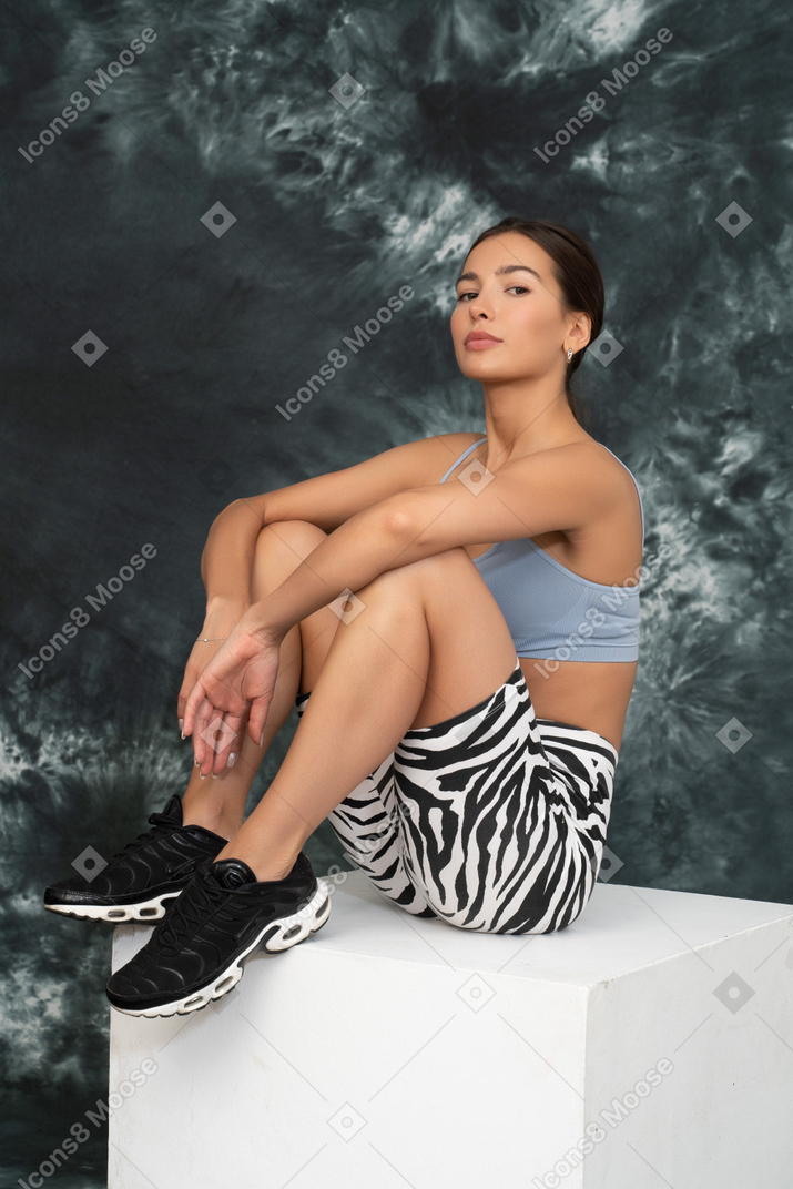 Retrato de una atleta femenina sentada con confianza en un cubo