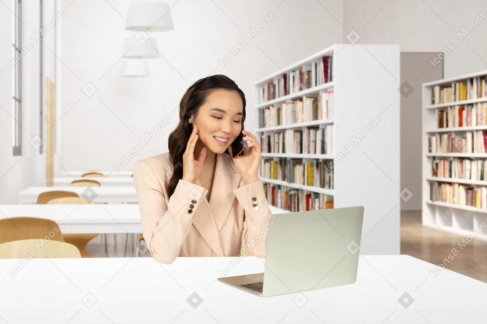 A woman talking on a cell phone while using a laptop