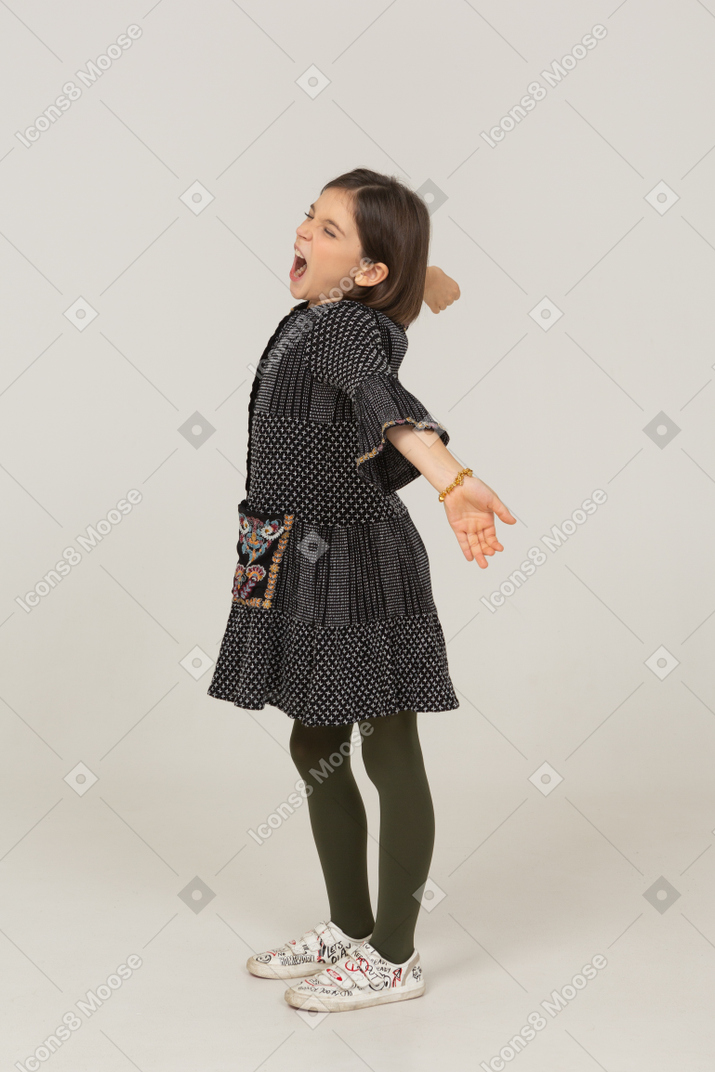 一个穿着裙子的小女孩的侧视图伸展她的背部和手臂