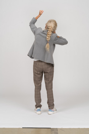拳を示すスーツを着た老婦人の背面図
