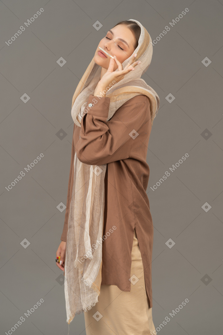 Young woman in beige clothes enjoying the smell of cigarette