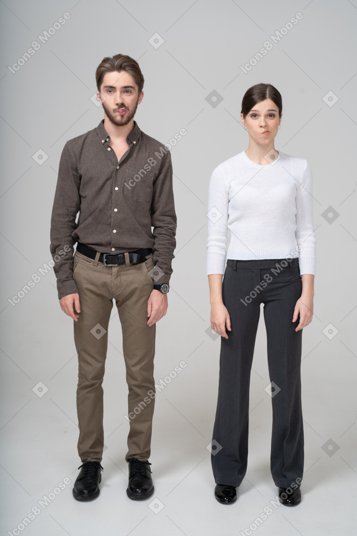 Front view of a confused grimacing young couple in office clothing