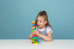 Surprised little girl playing with lego building blocks