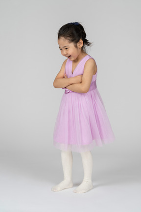 Niña en vestido rosa sonriendo con los brazos cruzados