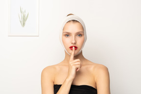 Young woman with head bandage making hush gesture