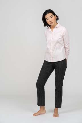 Vista frontal de una mujer en ropa de oficina con las manos detrás de la espalda