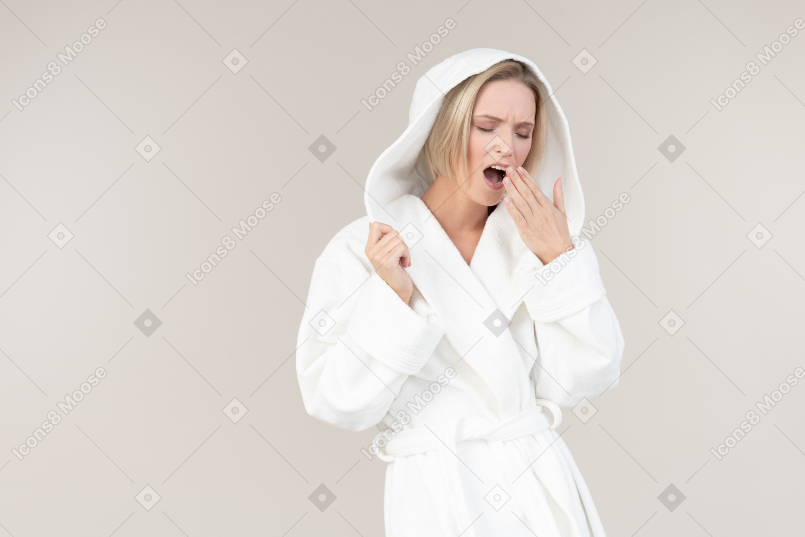 목욕 가운 하품과 손으로 입을 닫는 젊은 여자