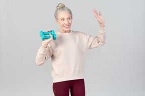 Sorridente donna anziana tenendo i pesi a mano in una mano