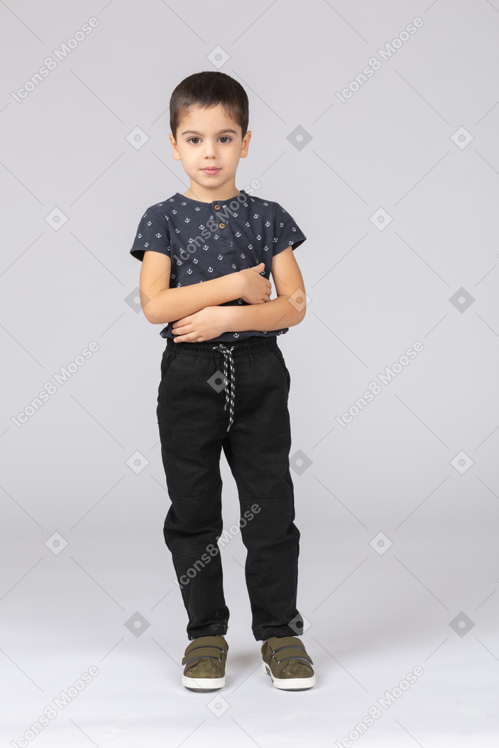 Front view of a cute boy standing with crossed arms and looking at camera