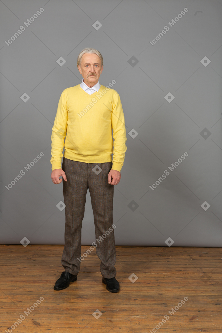 黄色のプルオーバーを着てカメラを見ている落ち込んでいる老人の正面図