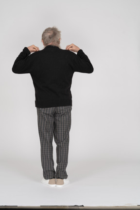 Homme âgé avec ses mains sur ses épaules debout avec son dos vers la caméra