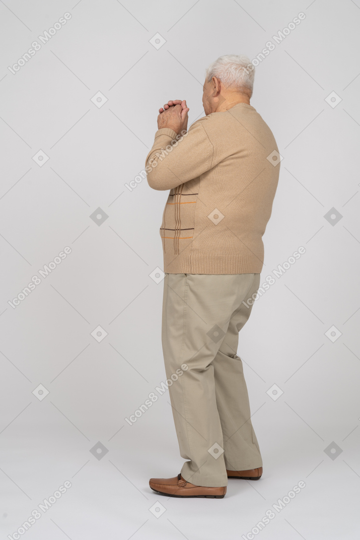 Side view of an old man in casual clothes dancing