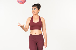 Junge indische frau in sporstwear werfen ball