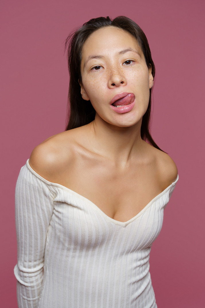 Front view of an impolite female licking her lips and looking at camera