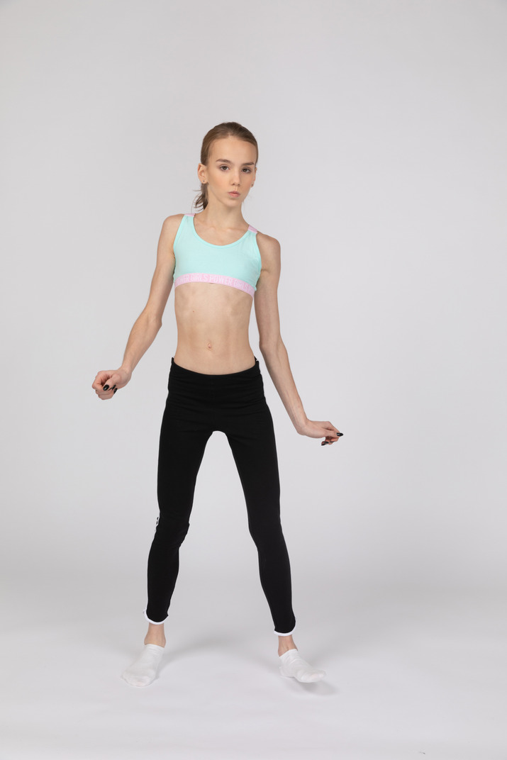 Front view of a surprised teen girl in sportswear outspreading her hands