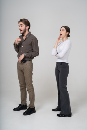 Vue de trois quarts d'un jeune couple bâillant en tenue de bureau