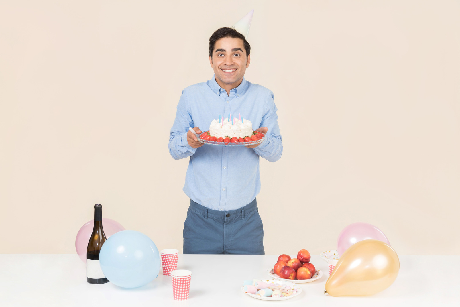 Young man standing at the birthday table and holding cake