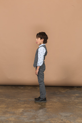 Side view of a cute boy in suit showing tongue