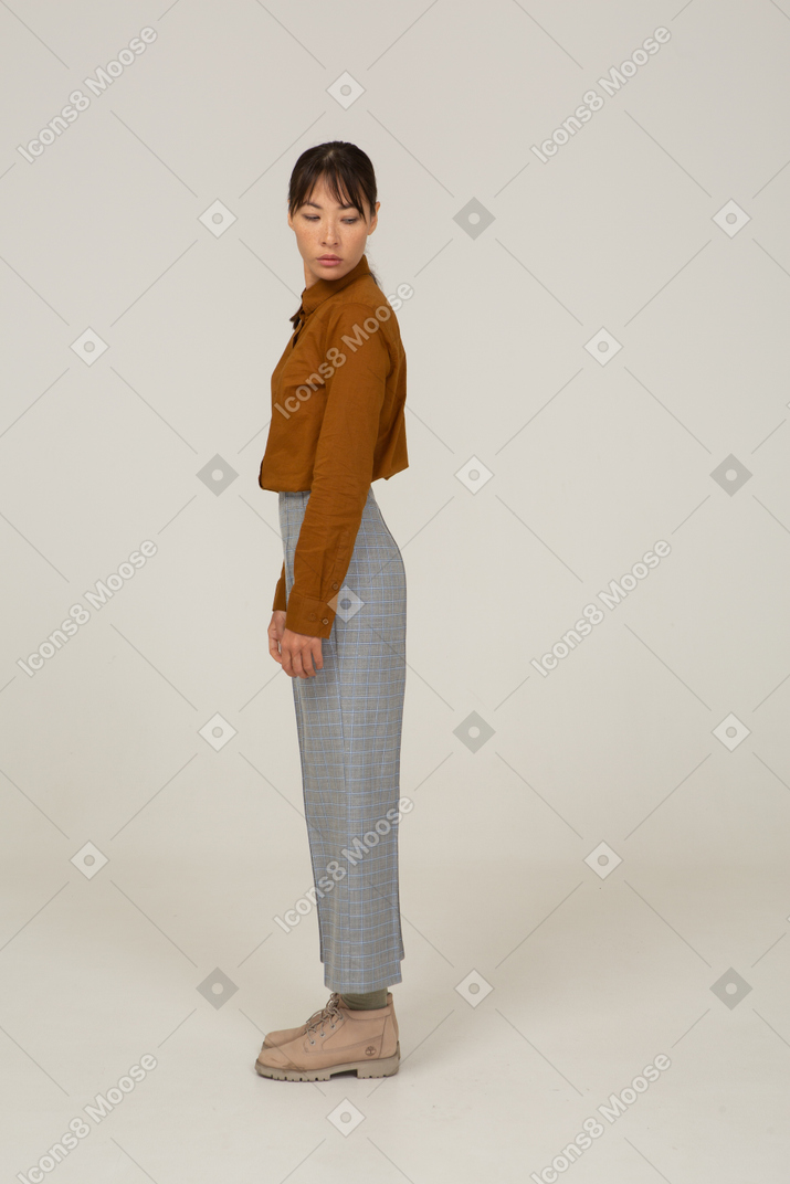 Side view of a young asian female in breeches and blouse turning away