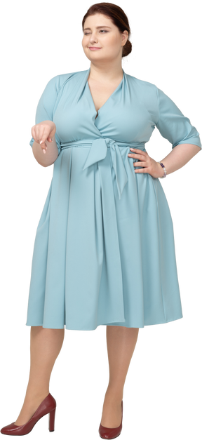 Vista frontal de uma mulher de vestido azul apontando para baixo com um dedo