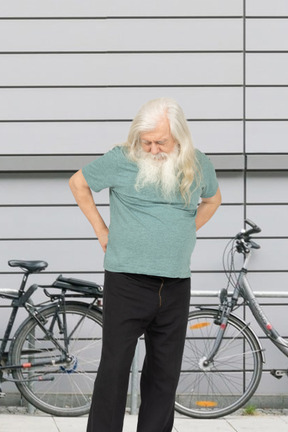 Old man standing in front of a bicycle looking at the ground