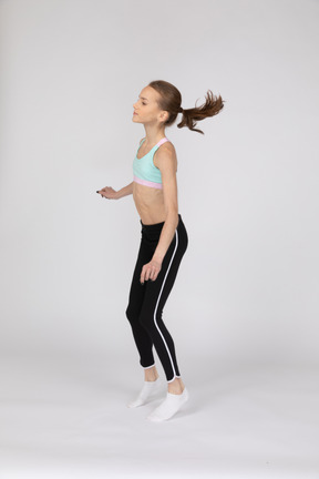 Side view of a teen girl in sportswear squatting and putting hands on hips