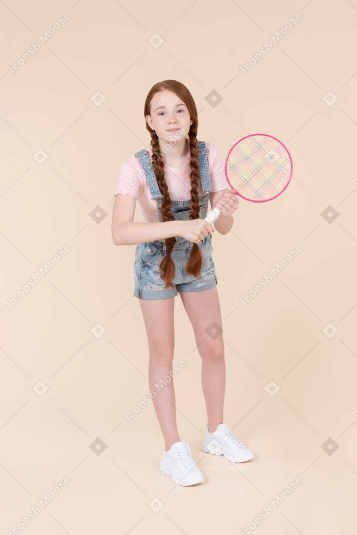 Optimistic teenage girl holding tennis racket