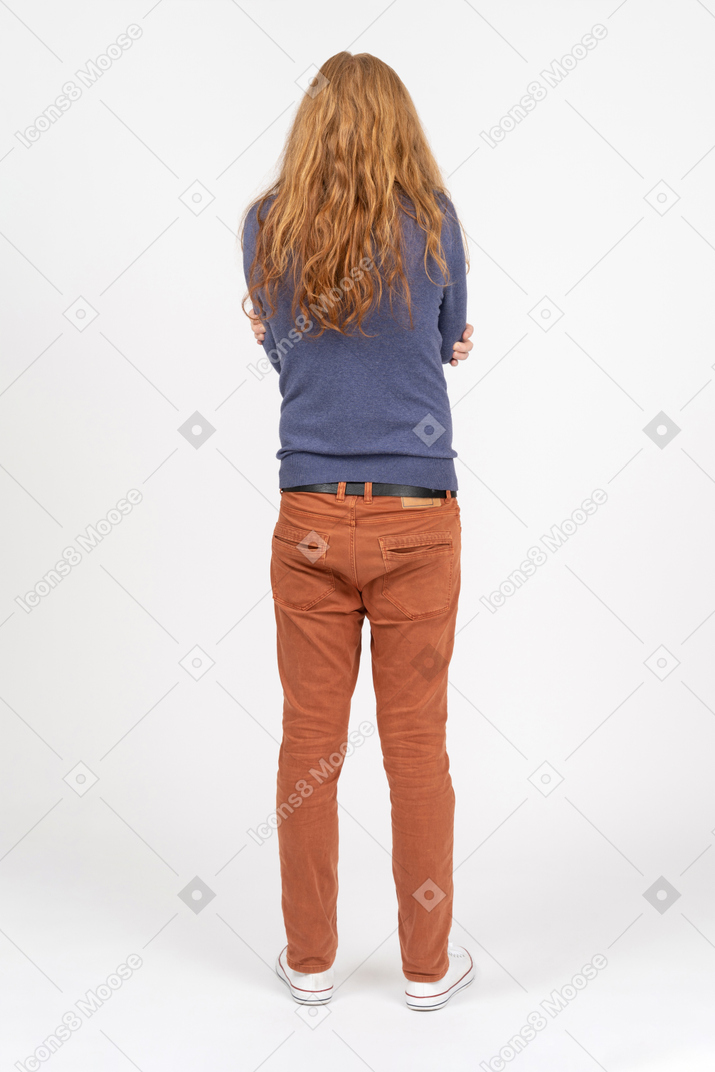 Rear view of a young man in casual clothes standing with crossed arms