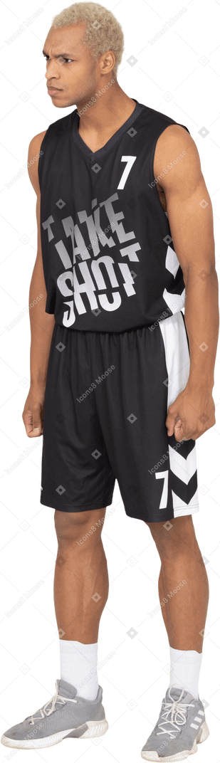 Vista di tre quarti di un giovane giocatore di basket maschio arrabbiato che stringe i pugni