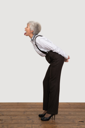 Side view of a crazy old lady in office clothing leaning forward