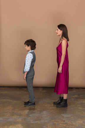 Femme en robe rouge et petit garçon debout de profil