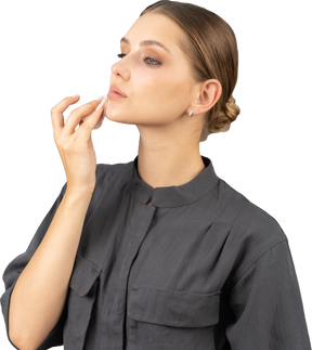 Трехчетвертный вид молодой женщины в комбинезоне, снимающей макияж