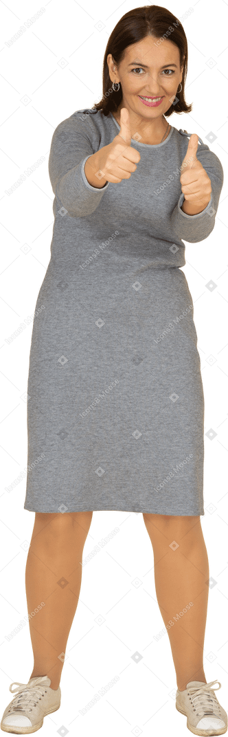 Vue de face d'une femme en robe grise montrant les pouces vers le haut