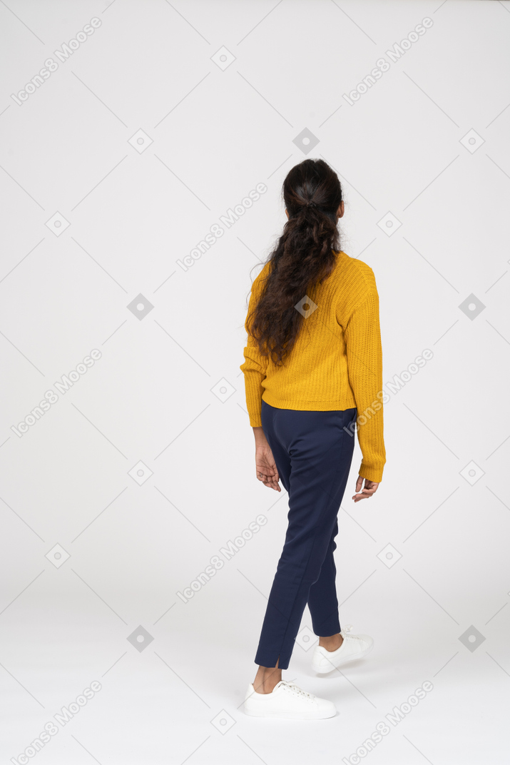 Vista posteriore di una ragazza in abiti casual che cammina