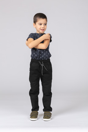 Vue de face d'un garçon mignon debout avec les bras croisés et regardant de côté