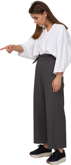 Three-quarter view of a young lady in office clothing pointing finger