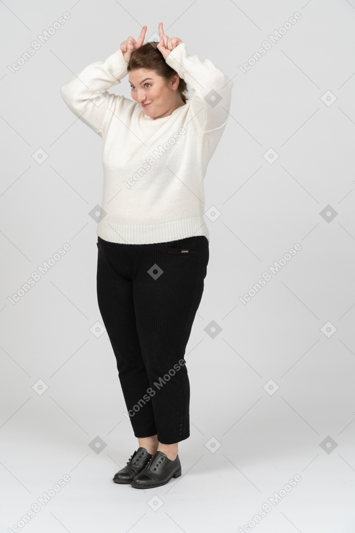 Vista frontale di una donna grassoccia in abiti casual che fa le corna