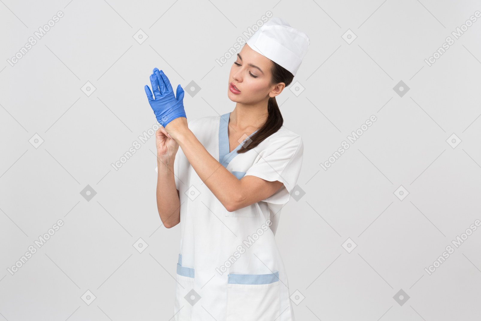 Attractive nurse in a medical robe taking off disposable gloves