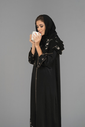 Jeune femme musulmane s'apprête à boire une tasse de café