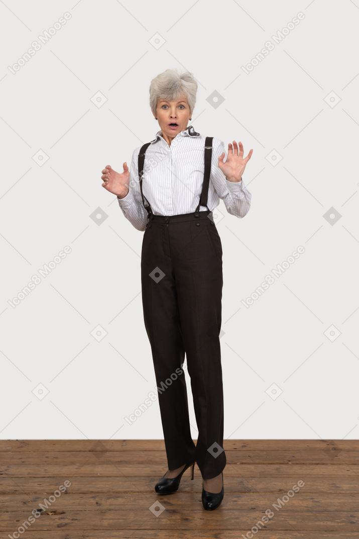 Front view of an astonished old lady raising and outspreading hands