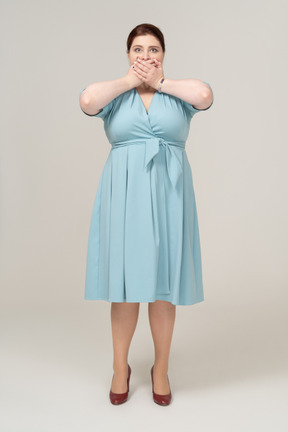 Front view of a woman in blue dress covering her mouth with hands