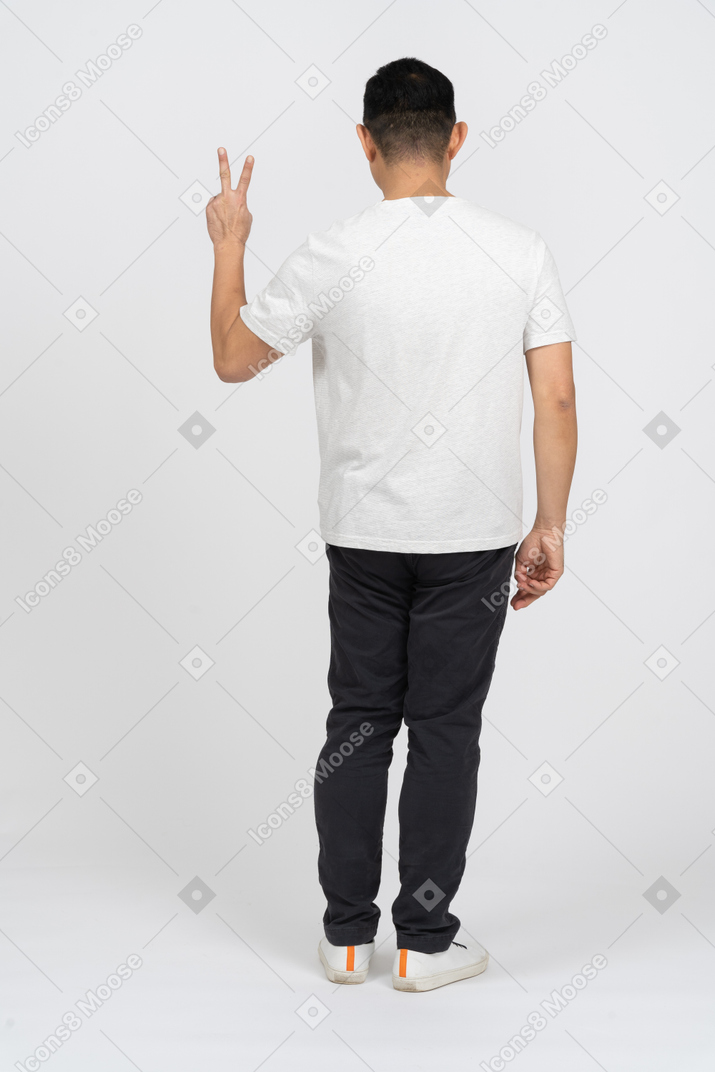 Rückansicht eines mannes in freizeitkleidung mit v-zeichen