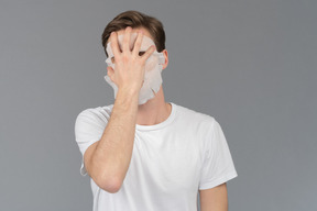 Front view of a young man taking off his facial mask