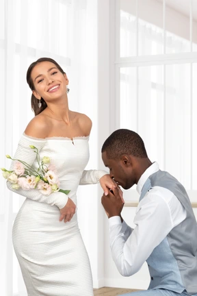 A man kneeling down next to a woman in a white dress