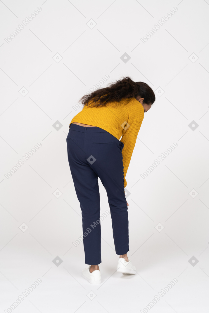 Vue arrière d'une fille en vêtements décontractés se penchant et touchant son genou douloureux